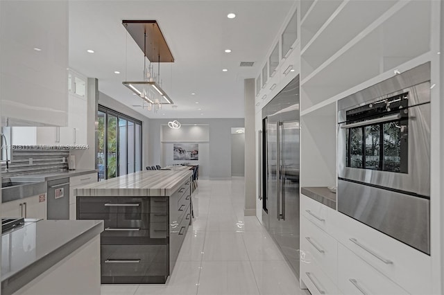 kitchen featuring appliances with stainless steel finishes, a kitchen island, light tile patterned floors, and white cabinets