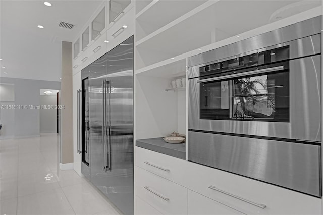 kitchen with white cabinetry, stainless steel appliances, and light tile patterned floors