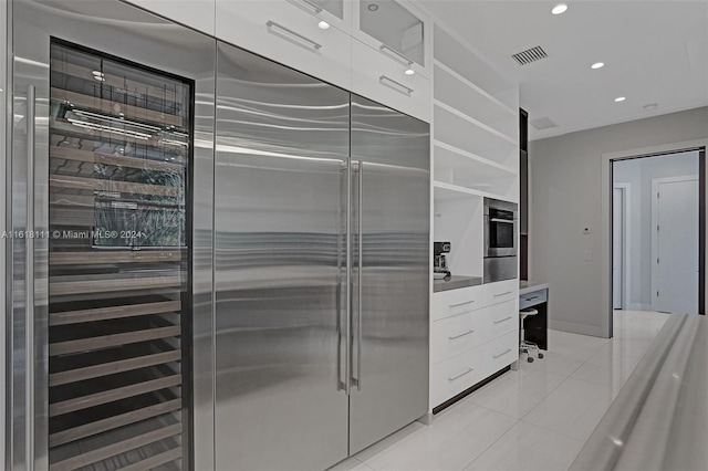 kitchen featuring appliances with stainless steel finishes, light tile patterned floors, and white cabinets