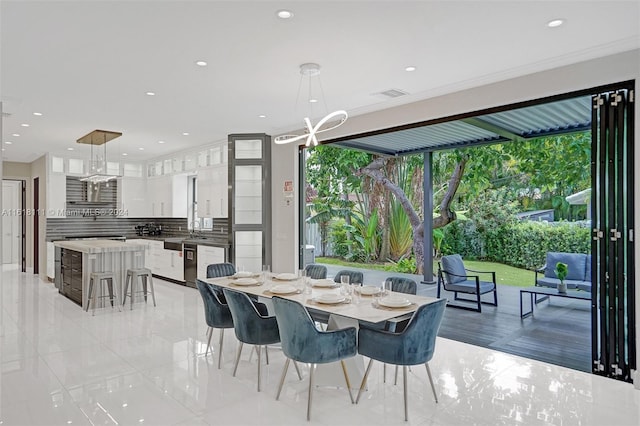 dining space with sink, crown molding, and an inviting chandelier