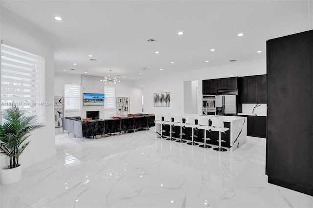 living room featuring a large fireplace, sink, and a notable chandelier