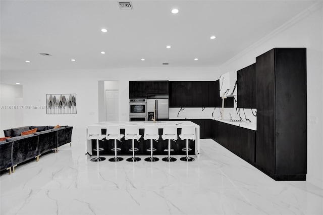 kitchen with appliances with stainless steel finishes, a kitchen bar, a center island with sink, and ornamental molding