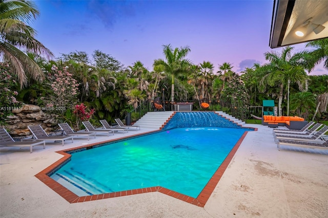 pool at dusk with an outdoor hangout area and a patio area