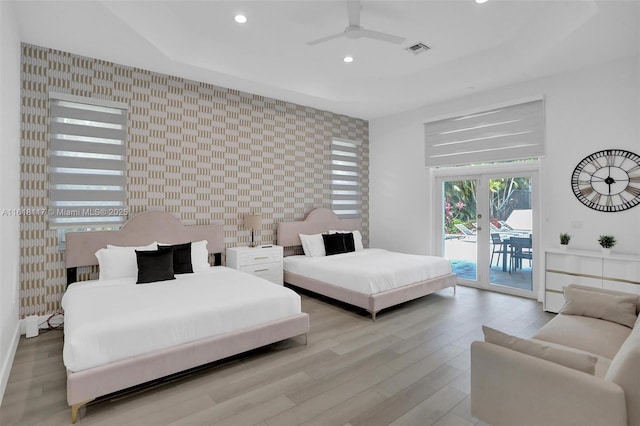 bedroom featuring french doors, a raised ceiling, ceiling fan, access to exterior, and light hardwood / wood-style floors