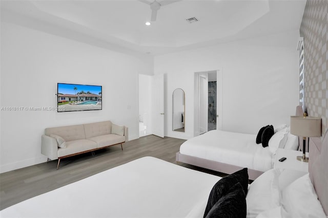 bedroom featuring a towering ceiling, wood-type flooring, and a raised ceiling