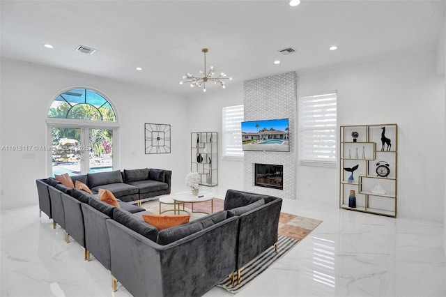 living room featuring a tiled fireplace, a chandelier, and french doors