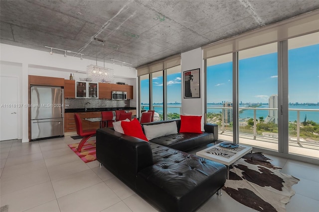 living room featuring light tile patterned flooring, a water view, and sink