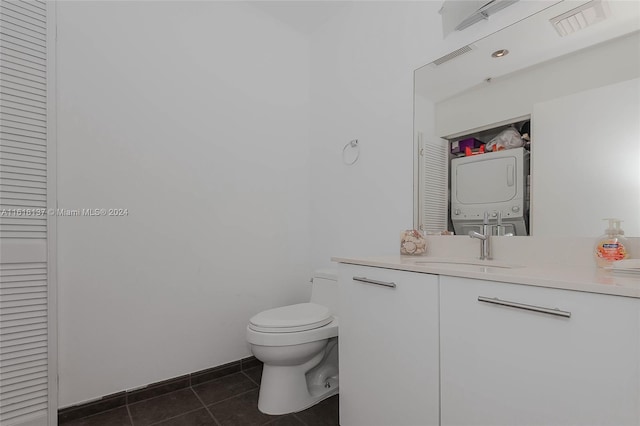 bathroom with stacked washer and clothes dryer, a closet, toilet, vanity, and tile patterned flooring