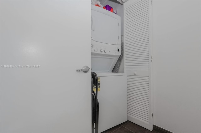 laundry room with stacked washing maching and dryer, laundry area, and dark tile patterned flooring