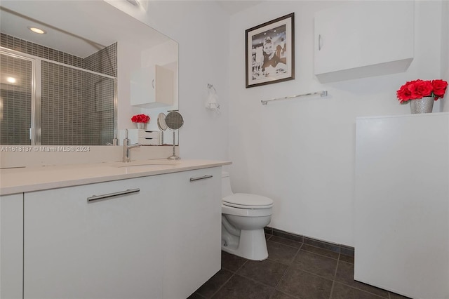 bathroom with toilet, a shower stall, vanity, and tile patterned floors