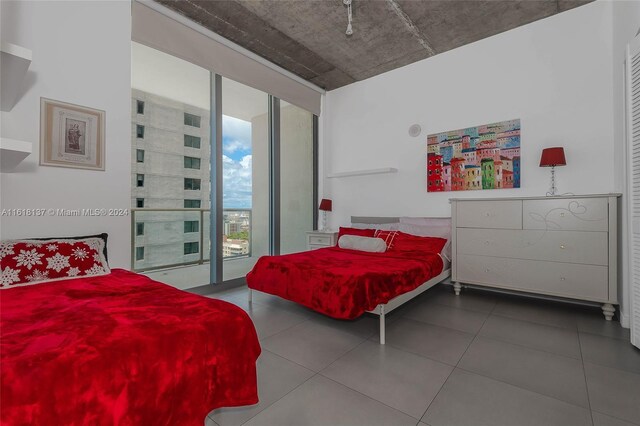 tiled bedroom featuring a wall of windows and access to outside