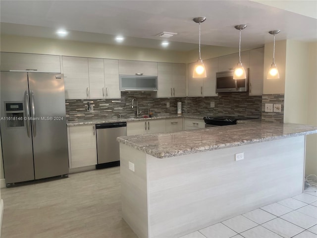 kitchen featuring tasteful backsplash, hanging light fixtures, sink, appliances with stainless steel finishes, and kitchen peninsula