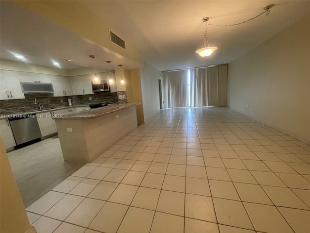 kitchen with decorative light fixtures, light tile patterned flooring, tasteful backsplash, stainless steel appliances, and stone counters