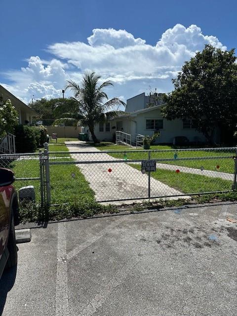 view of front of property featuring a gate, fence, and a front lawn