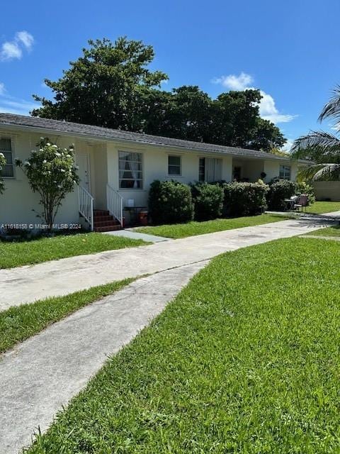 view of front of property featuring entry steps, concrete driveway, and a front lawn