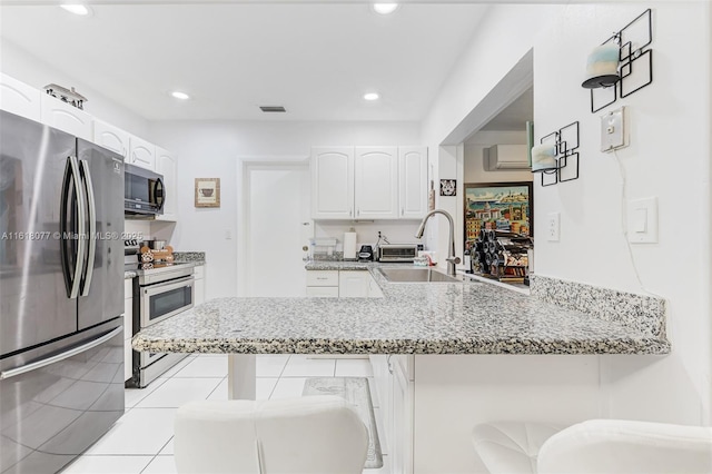 kitchen featuring white cabinets, kitchen peninsula, appliances with stainless steel finishes, and a kitchen breakfast bar