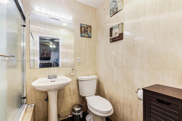 bathroom featuring walk in shower, ceiling fan, toilet, and tile walls