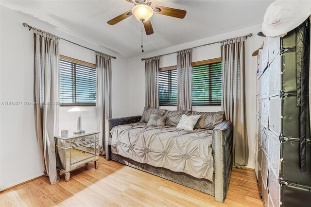 bedroom with hardwood / wood-style flooring, ceiling fan, and a textured ceiling