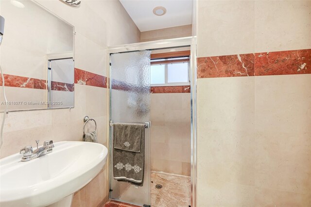 bathroom featuring an enclosed shower, tile walls, and sink