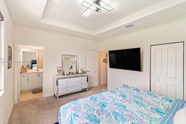 carpeted bedroom featuring connected bathroom, a raised ceiling, a closet, and sink