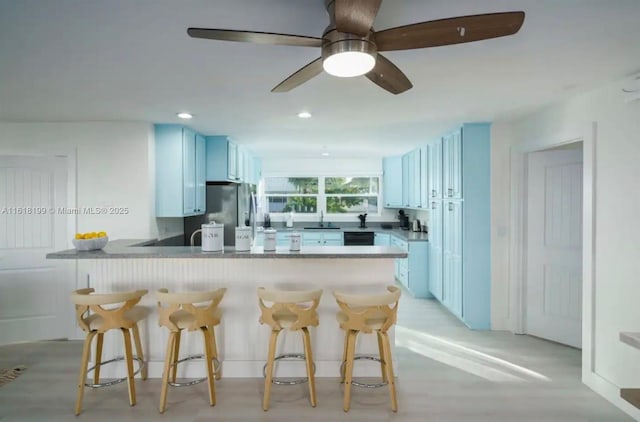 kitchen featuring white cabinetry, a kitchen breakfast bar, kitchen peninsula, and sink