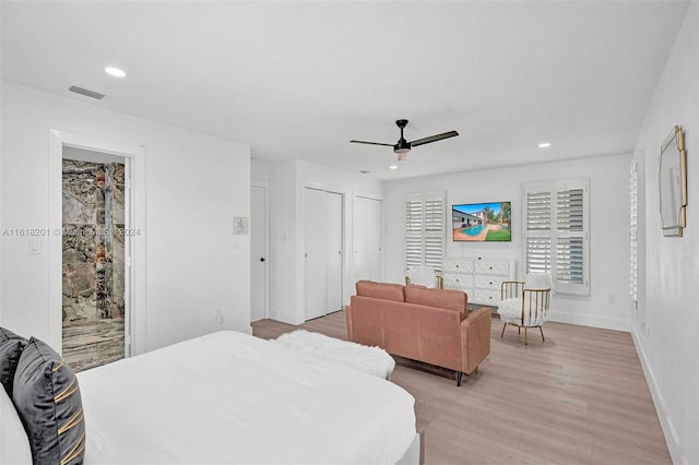 bedroom with ceiling fan, light hardwood / wood-style flooring, and multiple closets