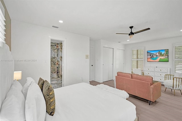 bedroom featuring multiple closets, ceiling fan, light hardwood / wood-style flooring, and access to outside