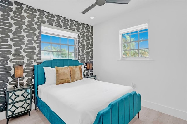 bedroom with ceiling fan, light hardwood / wood-style floors, and multiple windows