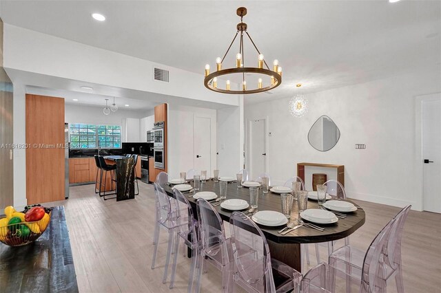 dining space with light hardwood / wood-style flooring and a notable chandelier