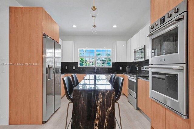 kitchen featuring white cabinets, a center island, tasteful backsplash, and appliances with stainless steel finishes