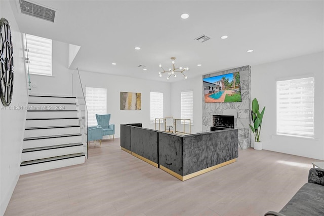 living room featuring light hardwood / wood-style floors, plenty of natural light, a notable chandelier, and a premium fireplace