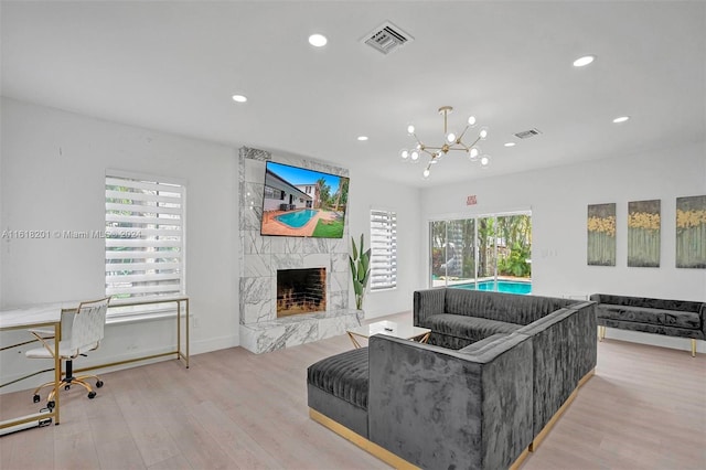 living room with a fireplace, light wood-type flooring, and an inviting chandelier