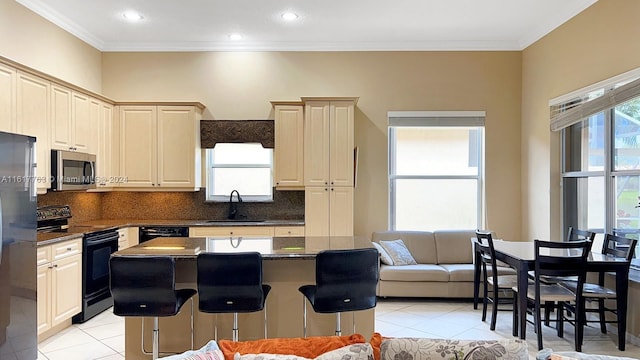 kitchen with a center island, black appliances, sink, tasteful backsplash, and a breakfast bar area