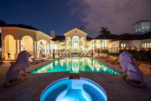 pool at twilight featuring a patio area and an in ground hot tub