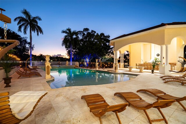 pool at dusk featuring a patio area