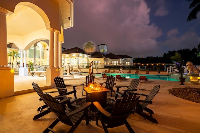 pool at dusk with a patio area and an outdoor fire pit