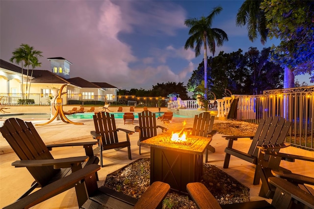 patio terrace at dusk featuring a community pool and a fire pit