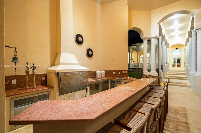 kitchen with sink, a breakfast bar area, kitchen peninsula, and ornate columns