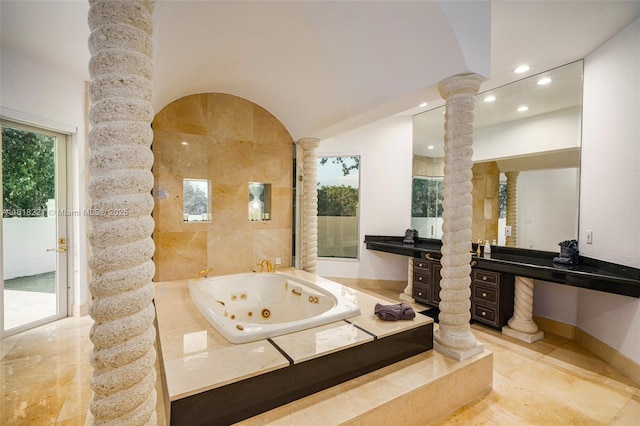 bathroom featuring vanity, tiled bath, and decorative columns