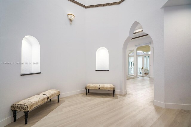 corridor with light hardwood / wood-style flooring and ornamental molding