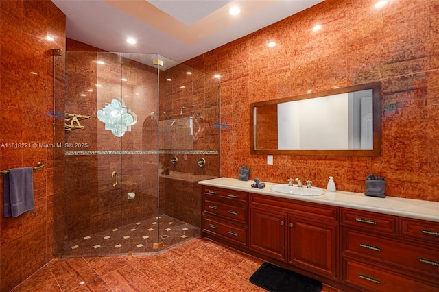 bathroom with vanity, a shower with door, and tile walls