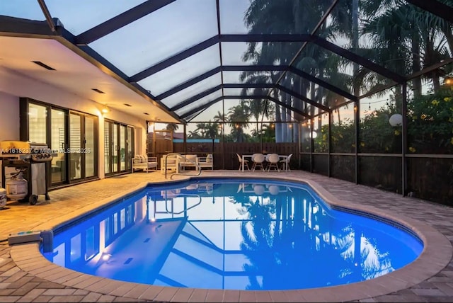 pool at dusk with a patio and glass enclosure