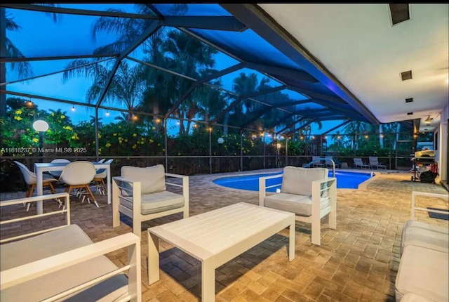 pool at dusk with a patio, an outdoor hangout area, and glass enclosure