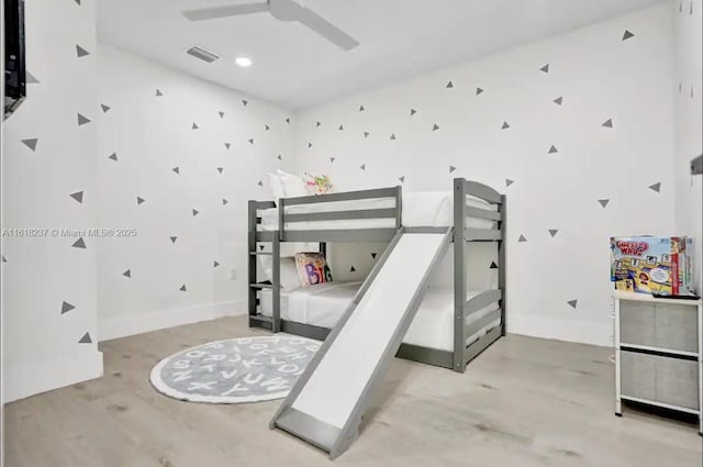 bedroom with light hardwood / wood-style floors, ceiling fan, and a high ceiling