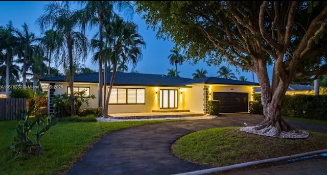 ranch-style home featuring a garage and a lawn