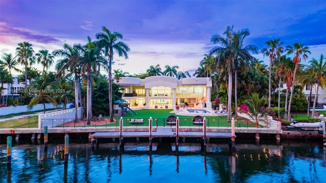 back house at dusk featuring a yard and a water view