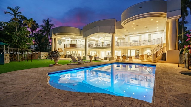 pool at dusk with a patio and a yard