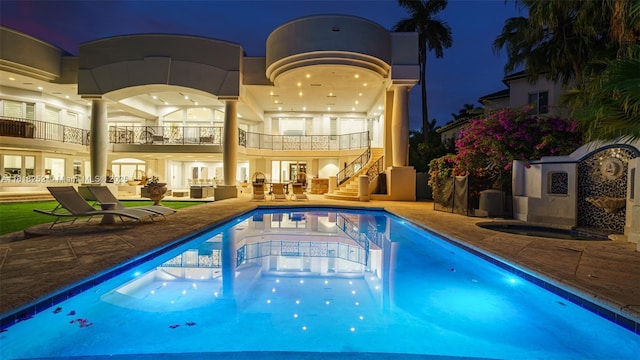 pool at night featuring a patio area