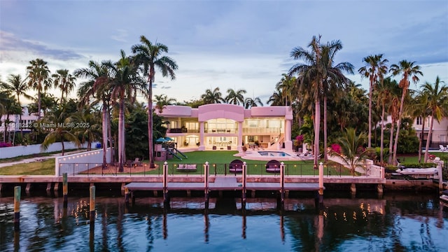 back house at dusk with a water view and a yard