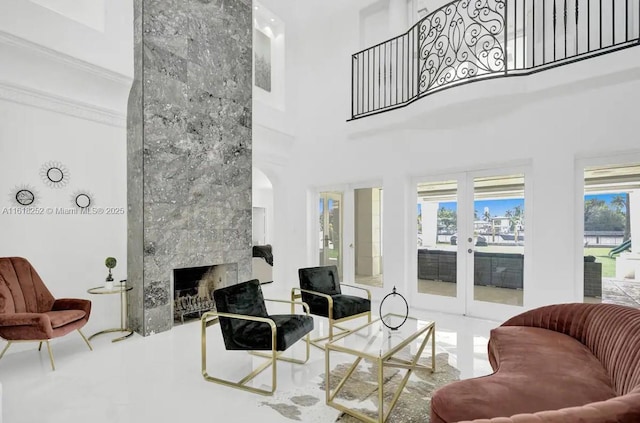 living room with a tiled fireplace, a high ceiling, a healthy amount of sunlight, and french doors